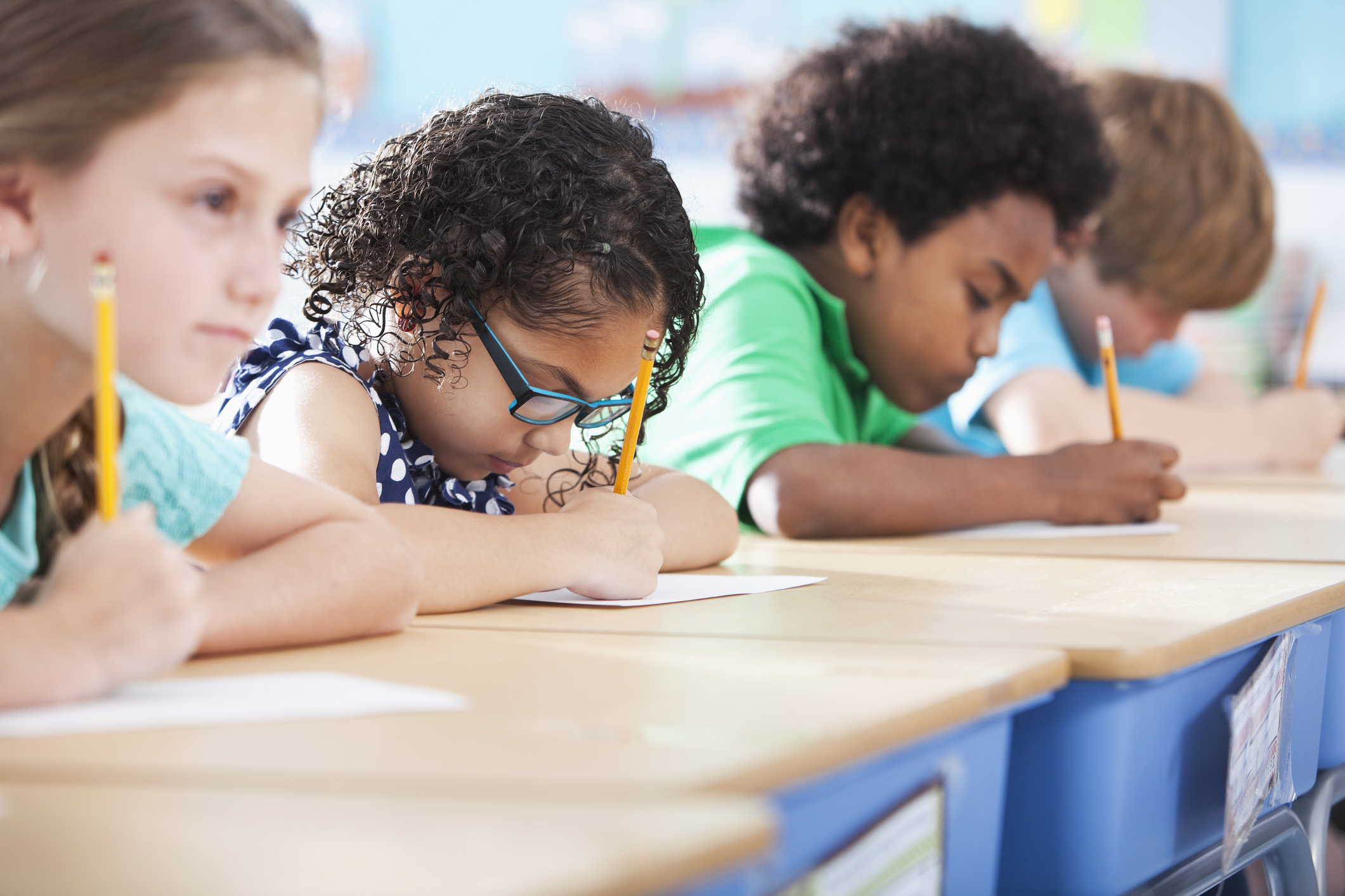 students sitting at a desk taking a test with pencil and paper